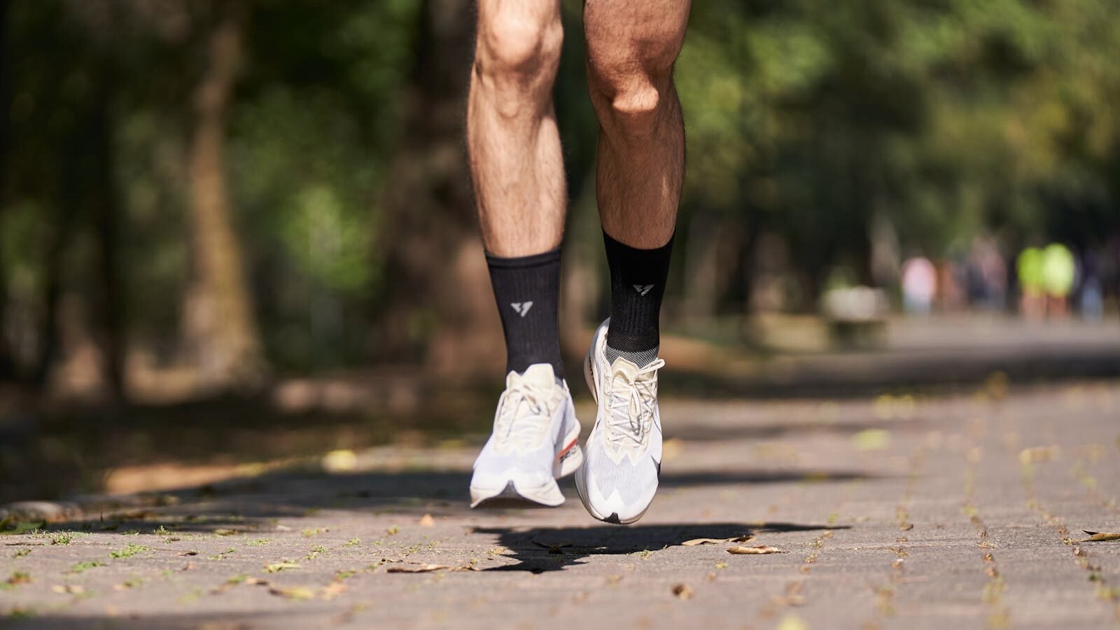 Close-up of a jogger's feet in mid-air on a sunny day in the park.