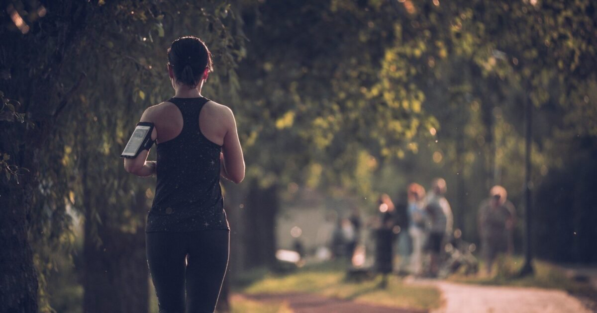 woman in black tank top and black pants walking on sidewalk during daytime