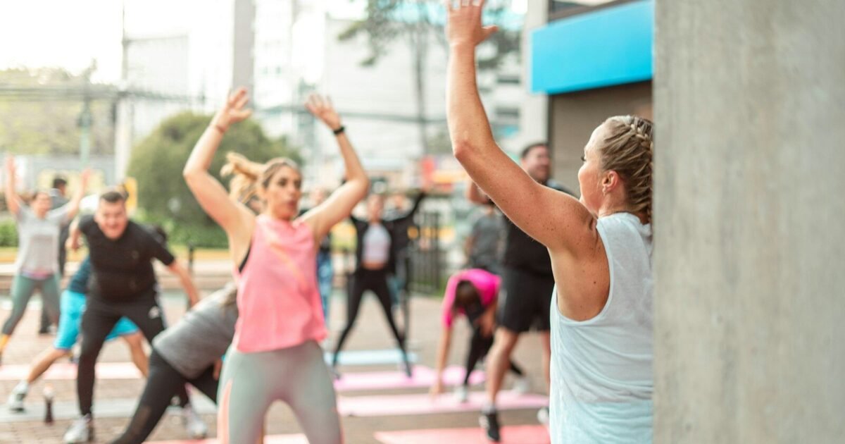 a group of people doing yoga outside on a sunny day
