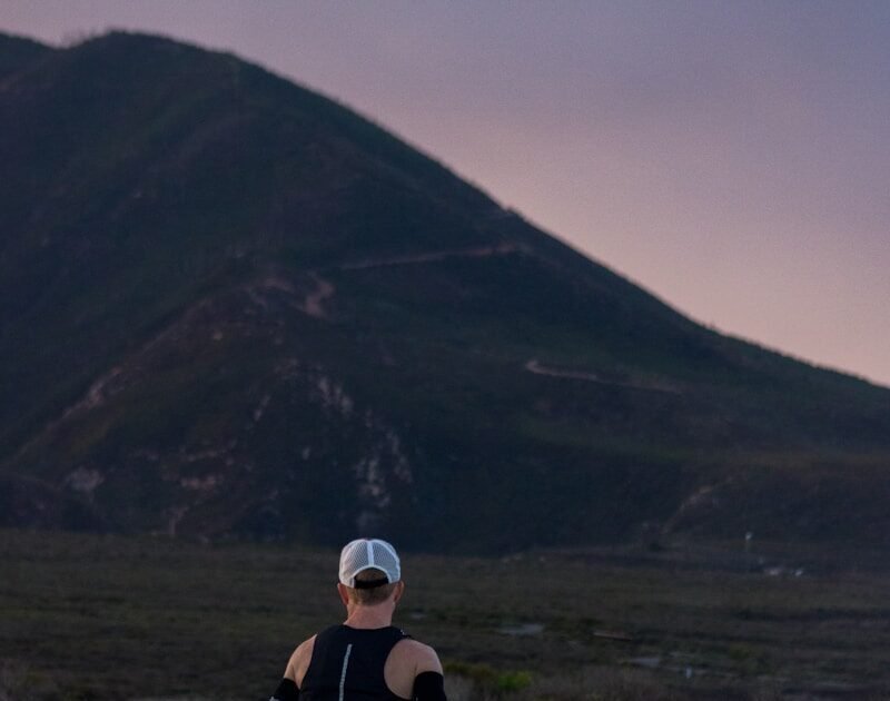 woman jogging on gray road across mountain during daytime