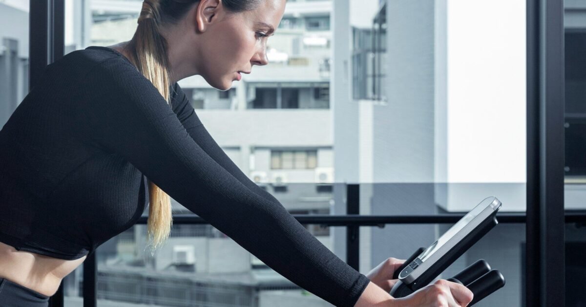 a woman on a stationary bike using a tablet