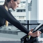 a woman on a stationary bike using a tablet