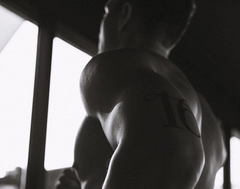 A muscular man exercises in a darkened gym.