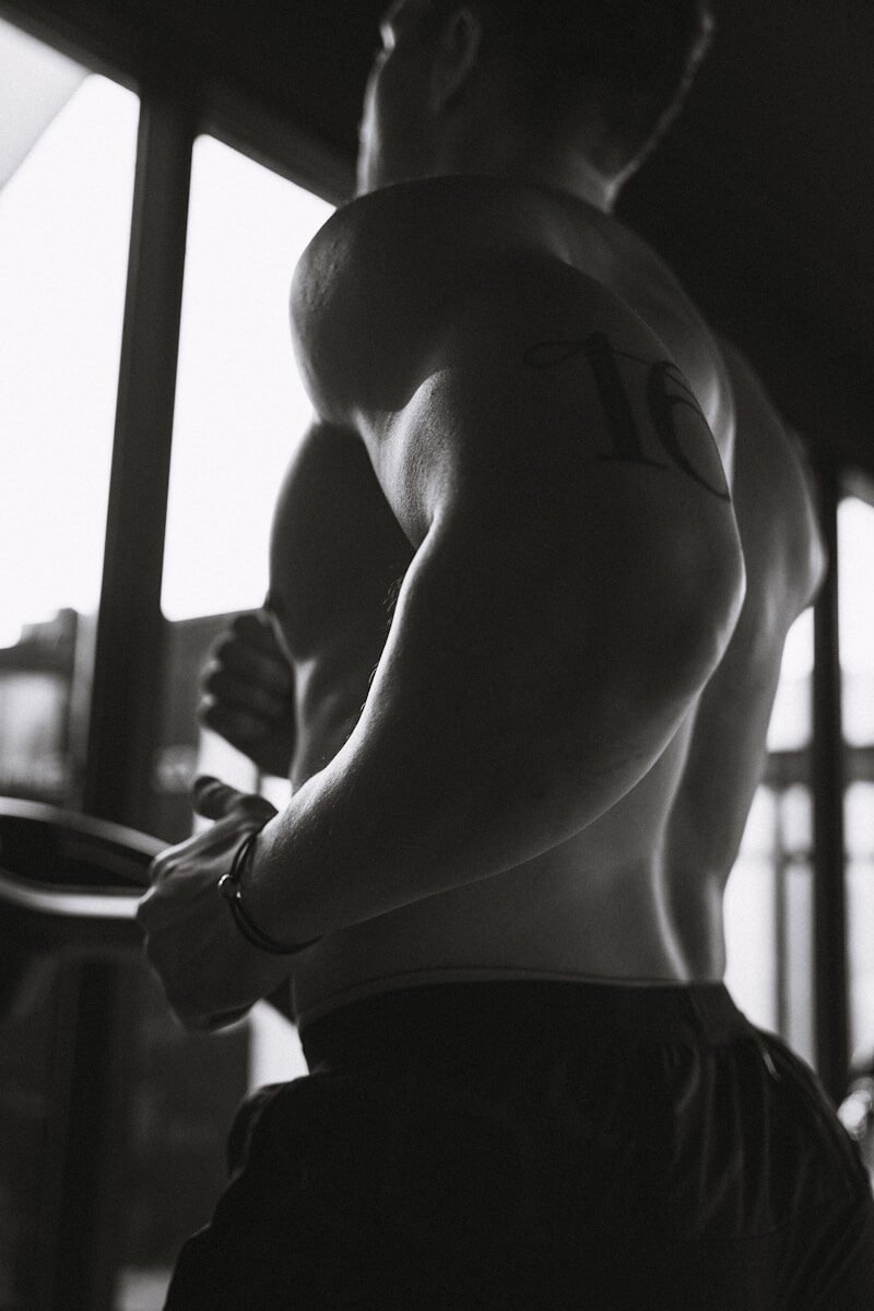 A muscular man exercises in a darkened gym.
