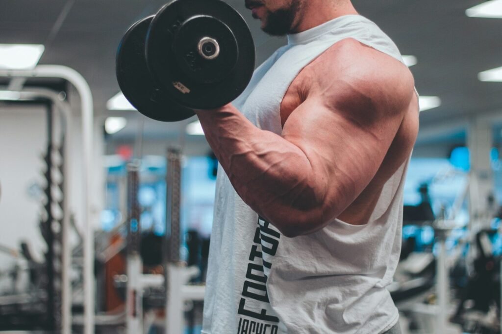 man in white tank top lifting black dumbbell