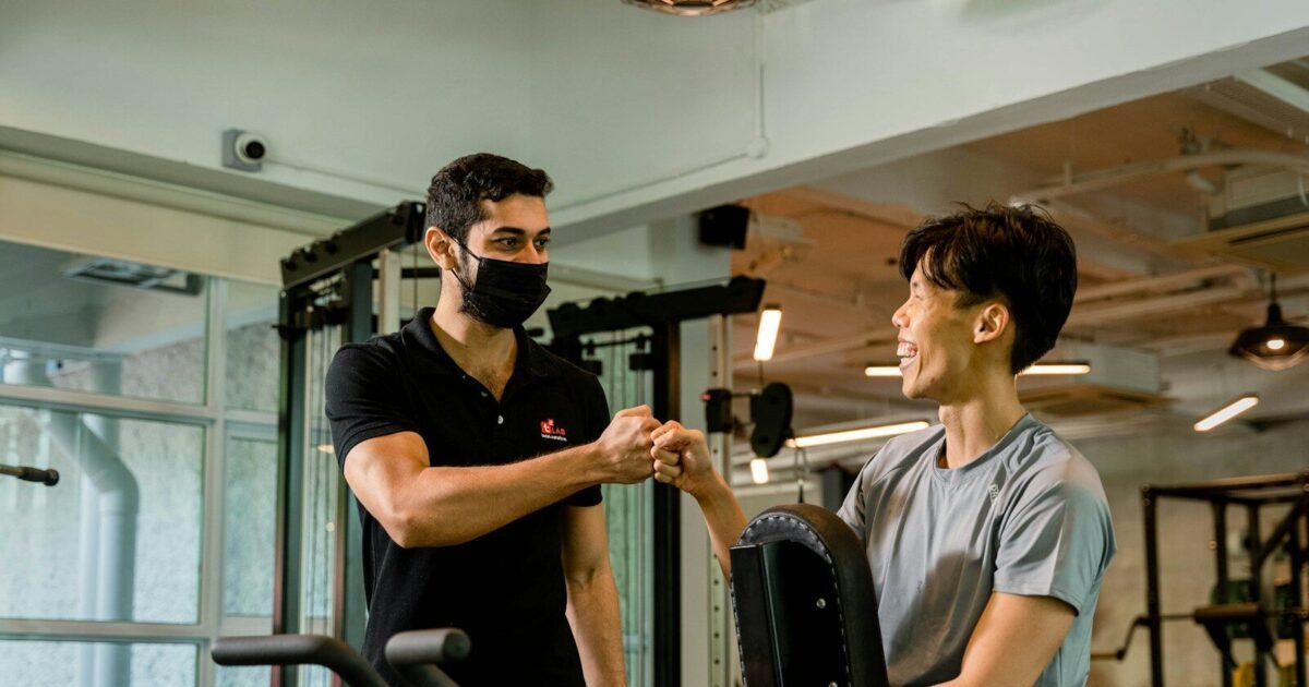 Trainer and client fist-bumping at the gym.