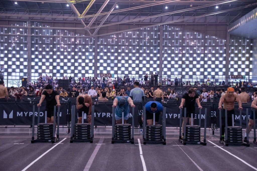 Athletes compete by pushing weighted sleds indoors.