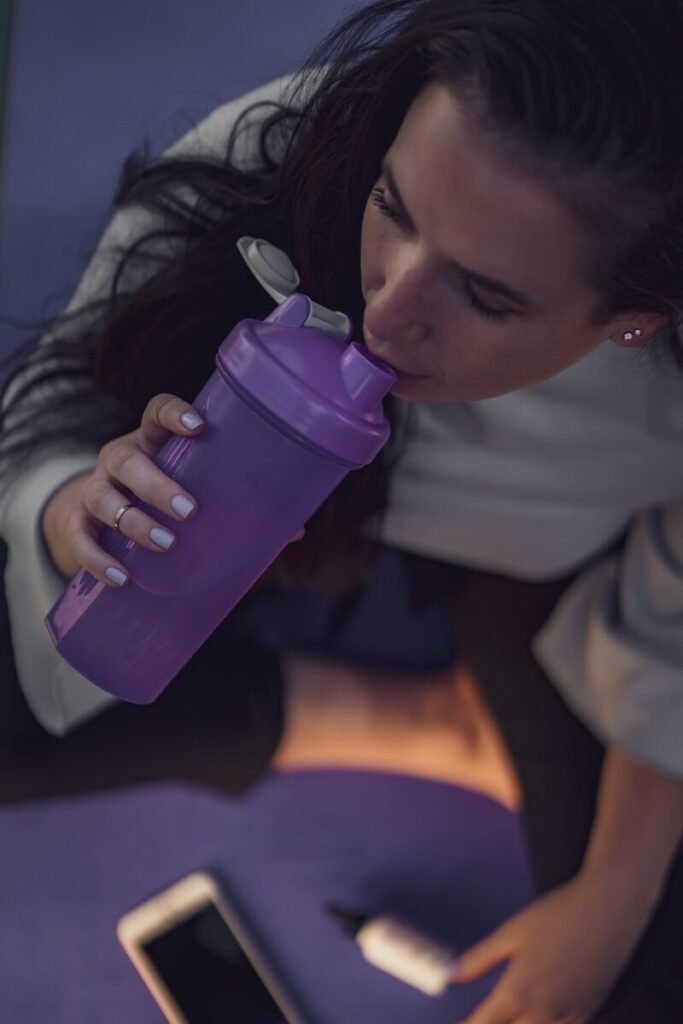 woman in white sweater holding purple water bottle