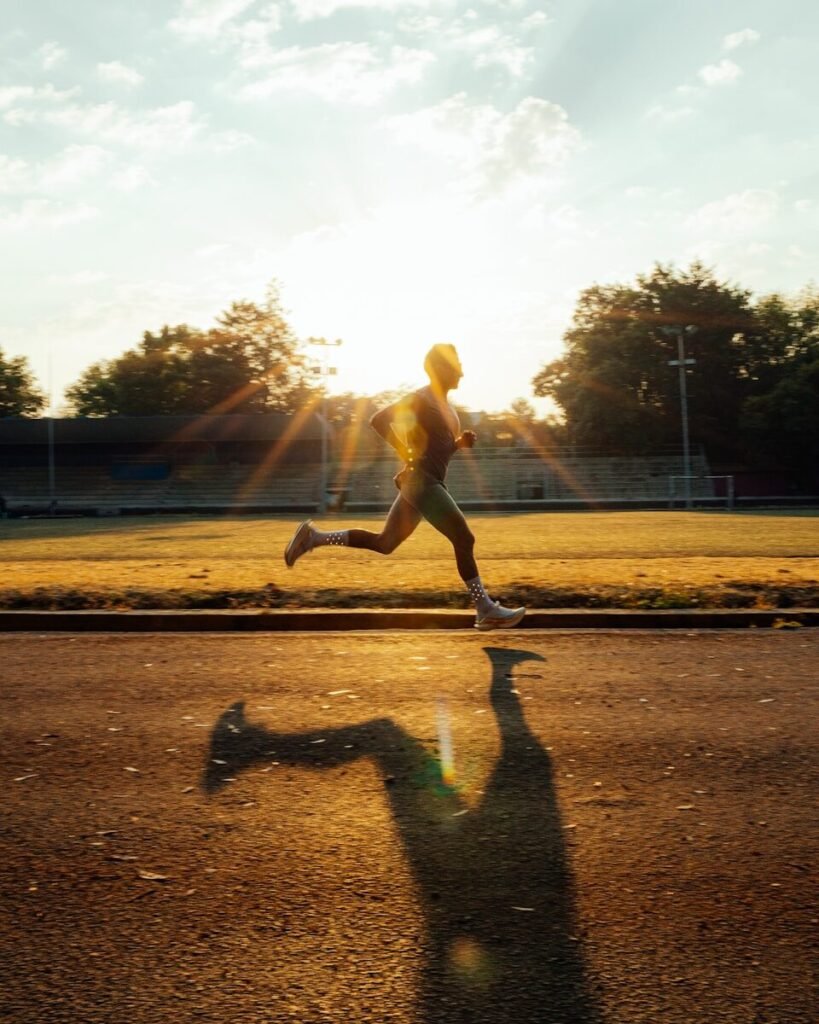 Atleta em pista de atletismo focando em aumentar a distância na corrida.