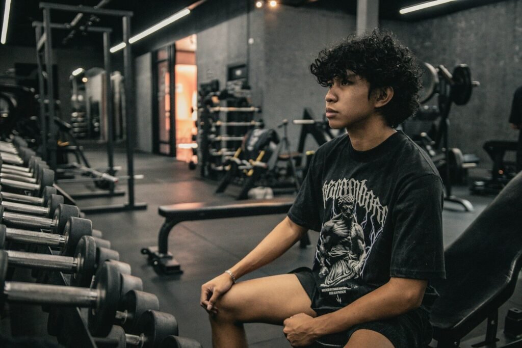 Jovem sentado em um banco de academia iniciando seu treino de musculação para adolescentes