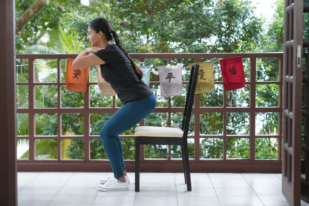 Pessoa em pé ao lado de uma cadeira praticando exercícios simples para queimar calorias.