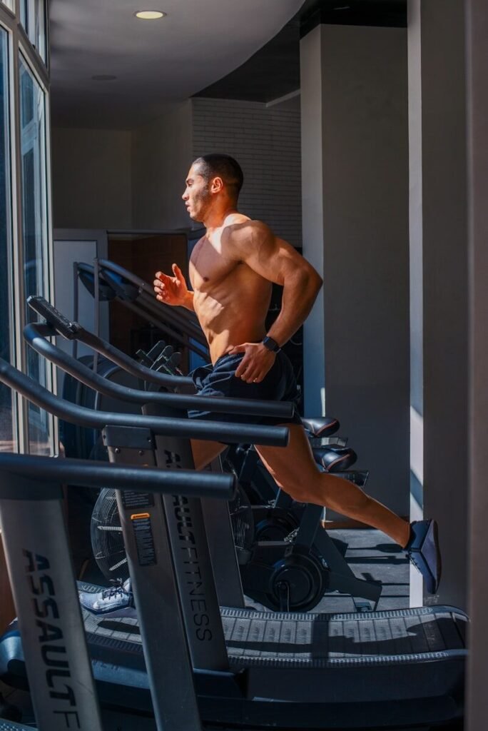 Homem correndo na esteira da academia, praticando cardio para condicionamento físico.