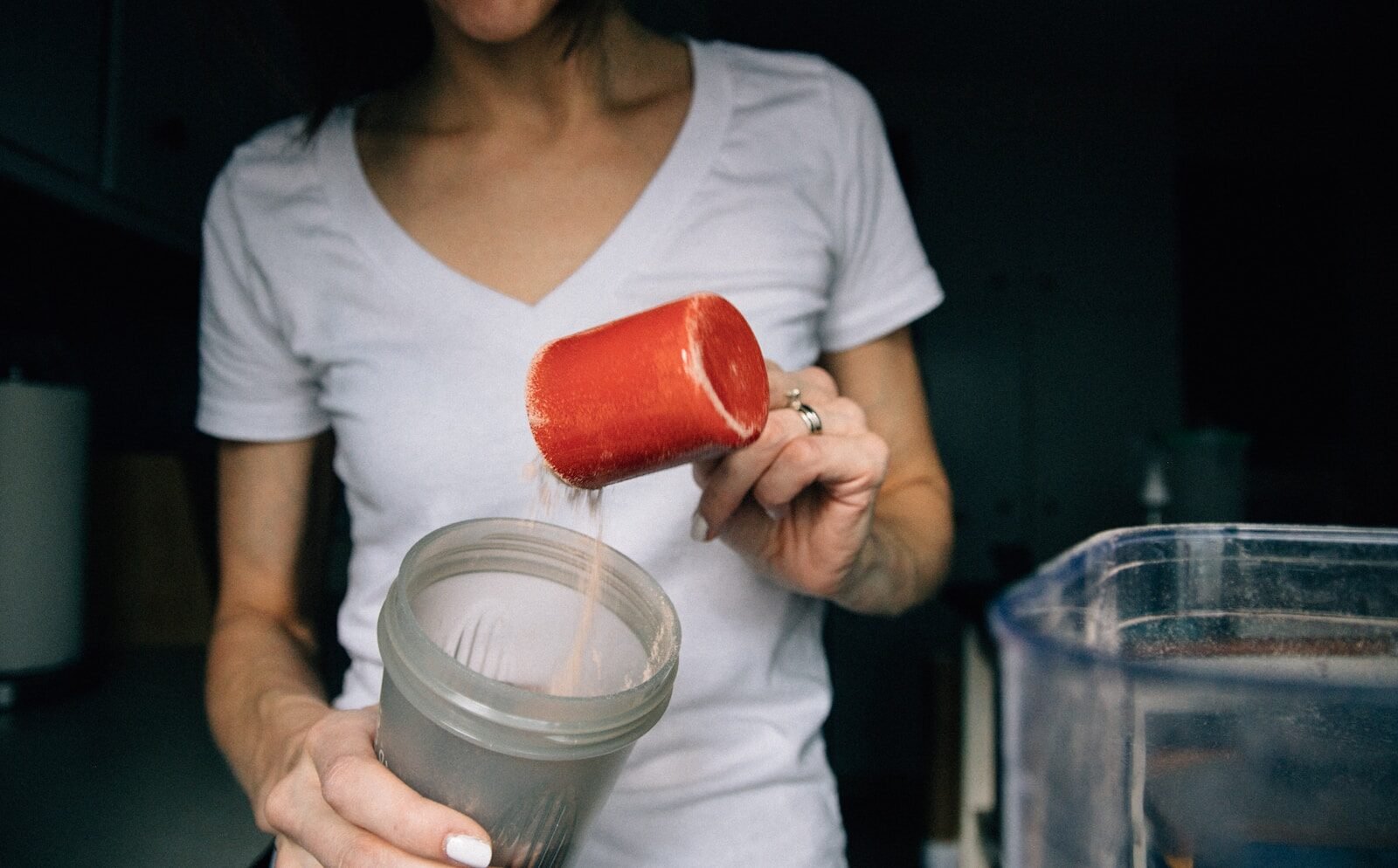 Mulher segurando copo de suplemento Whey Protein após treino de academia