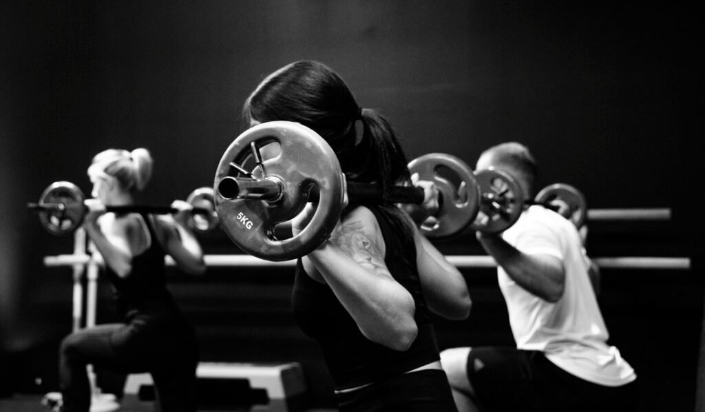 Grupo de pessoas treinando com barras, exemplificando a versatilidade do treino de corpo inteiro