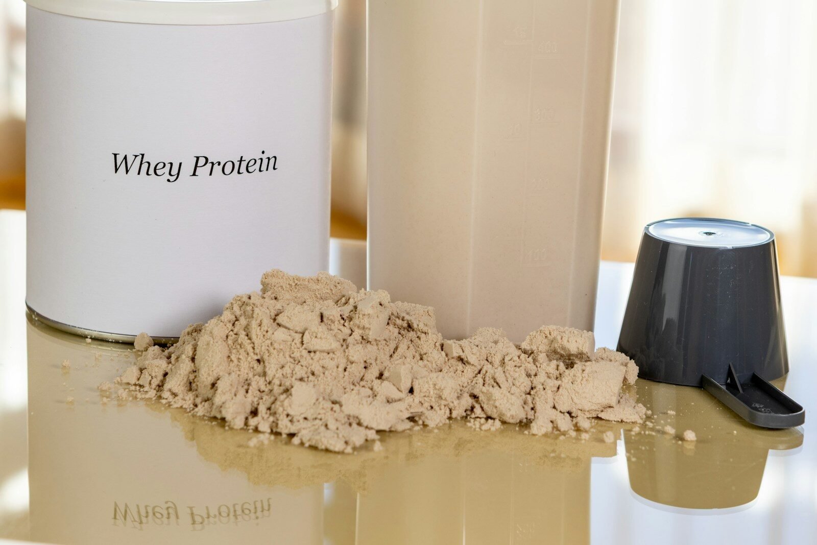 Pó de Whey Protein concentrado ao lado de coqueteleira para preparo de suplemento